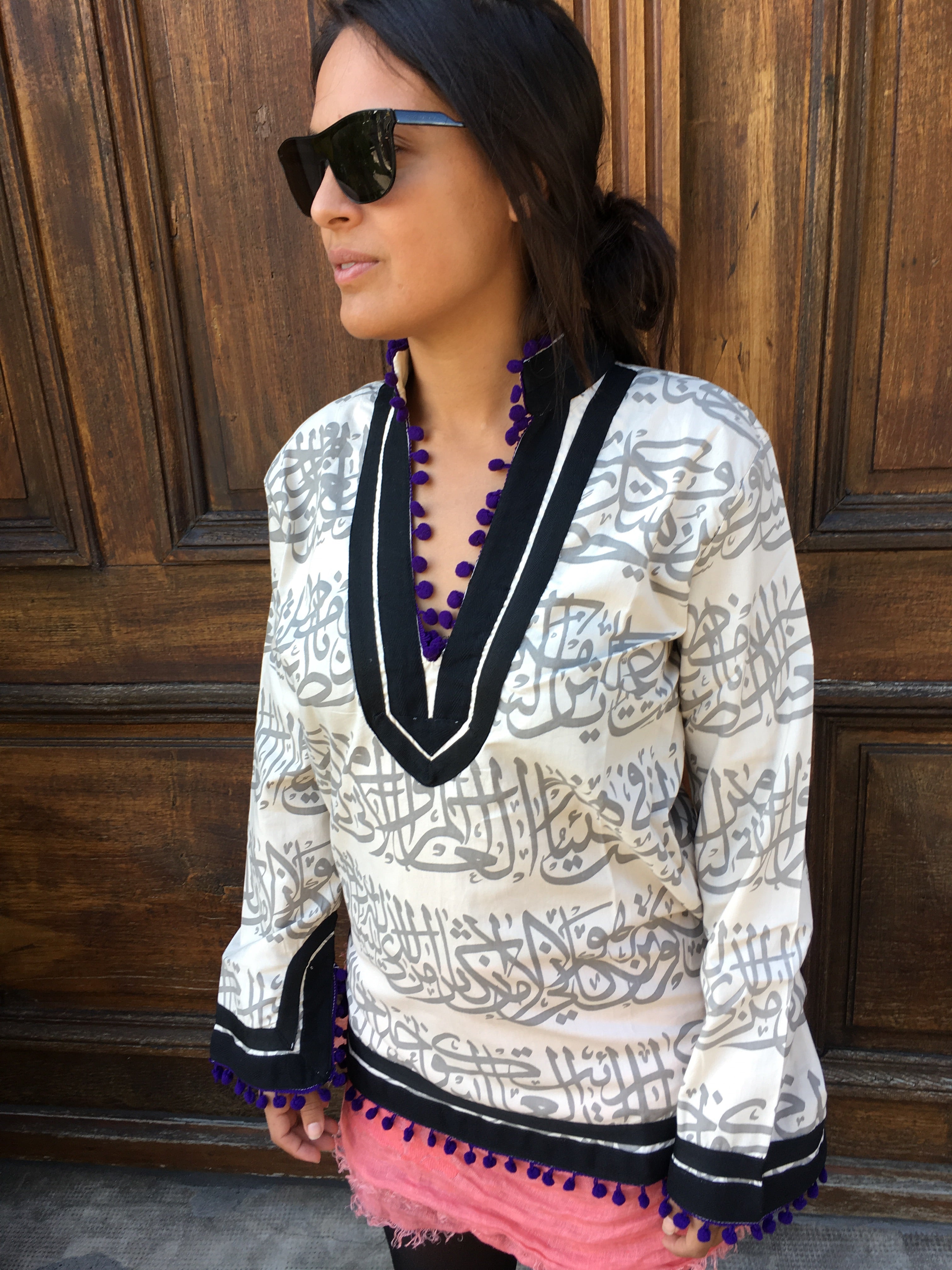 Rumi Tunic, grey print, black collar, purple pompoms.