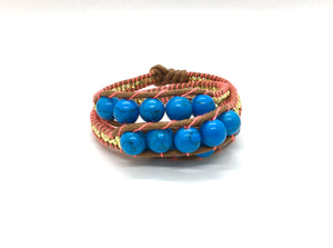 Wraparound bracelet medium blue marble bead, gold resin side bead brown cord fluo coral thread.