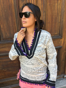 Rumi Tunic, grey print, black collar, purple pompoms.