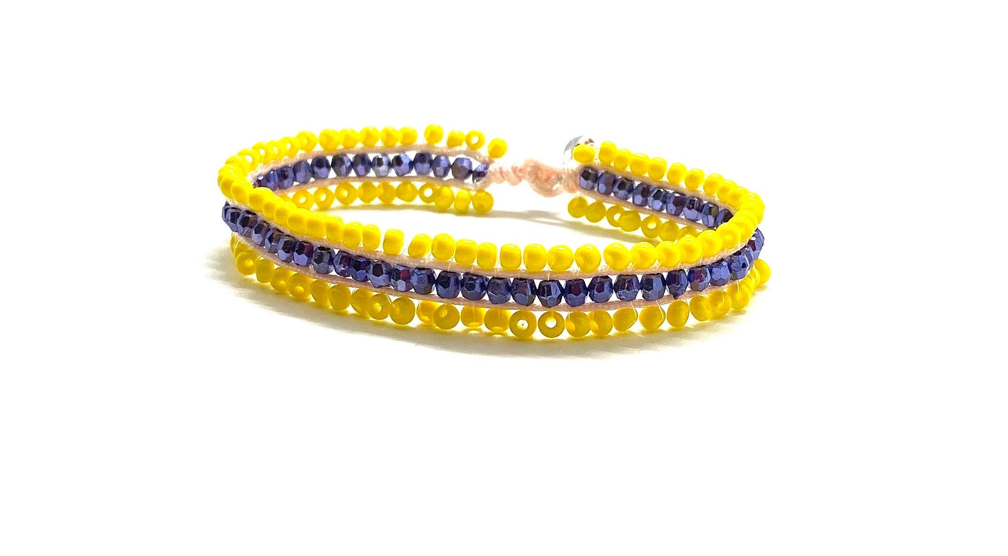 Beaded bracelet, yellow and purple seed beads and yellow cord.